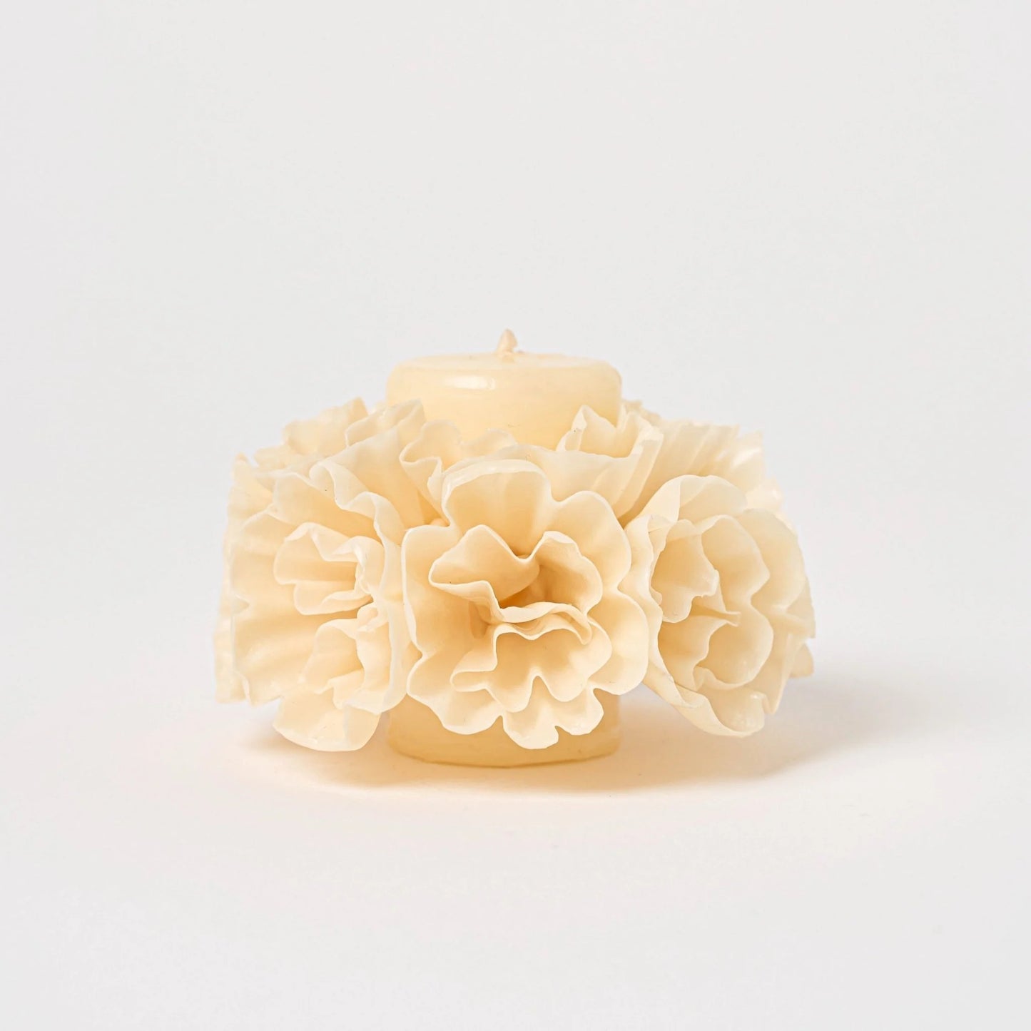 Carved ivory beeswax skirted candle with floral sculpted details on white background