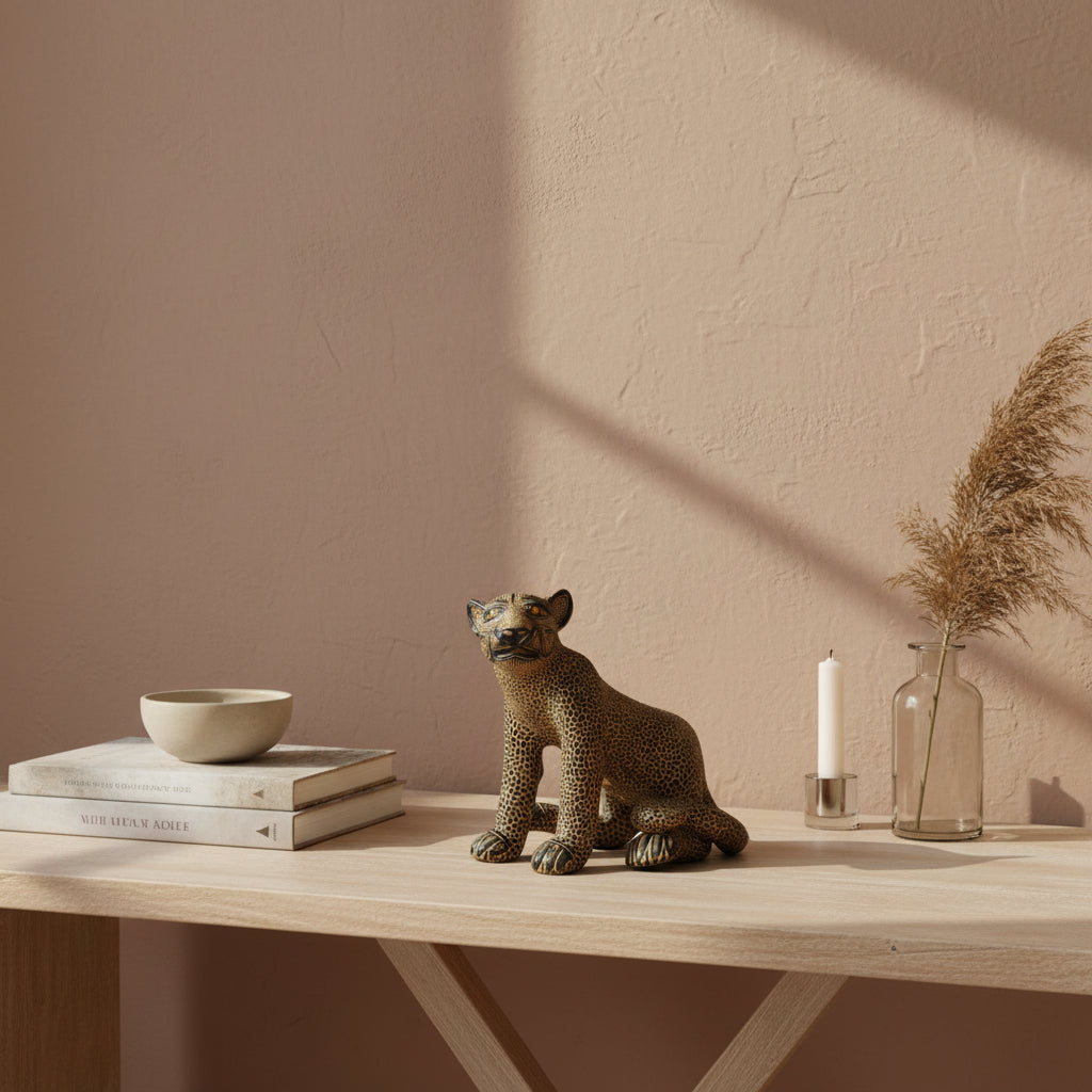 Seated Mayan jaguar clay sculpture styled on a wooden console with books, candle, and ceramic decor