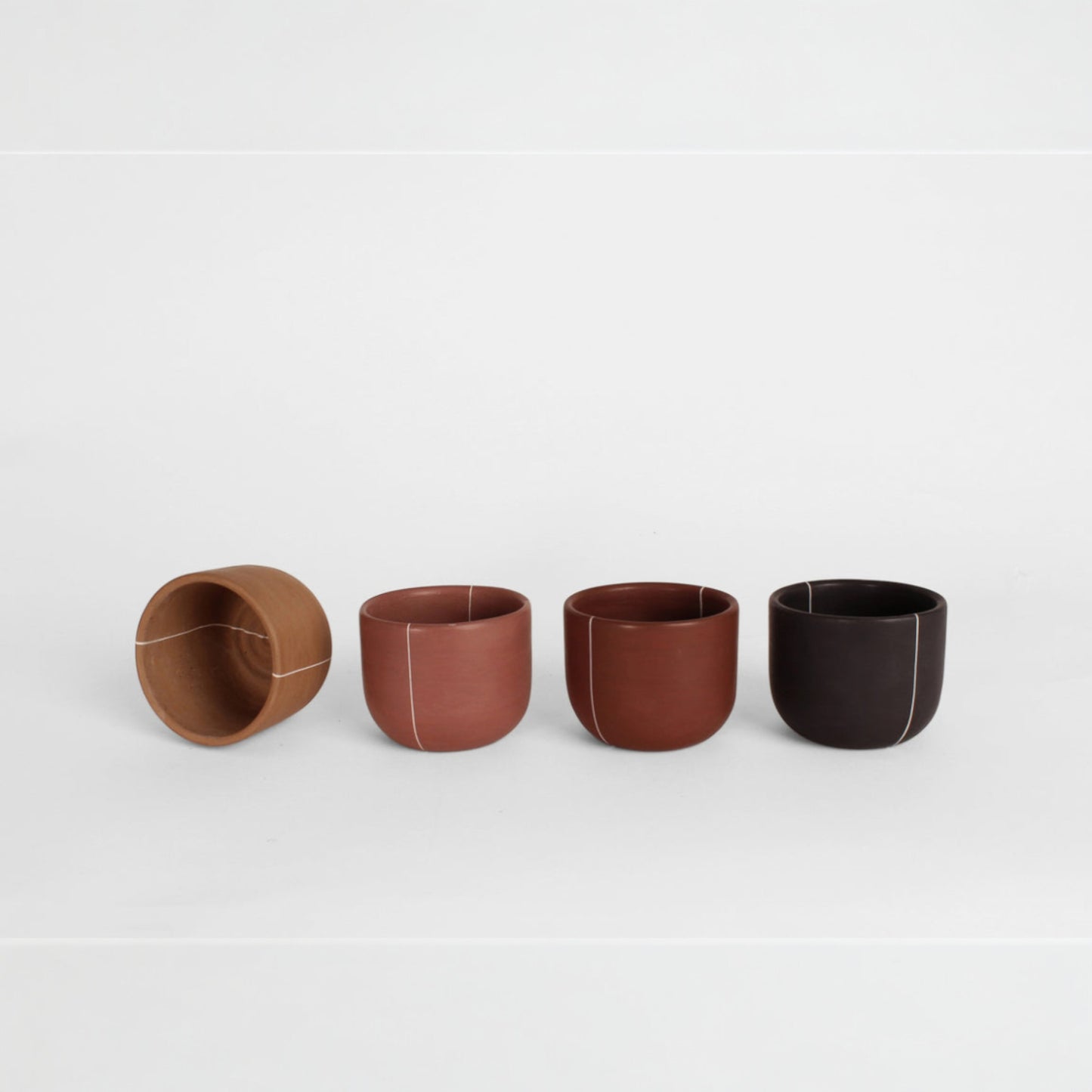 Set of artisanal clay cups arranged in a row in natural earth tones
