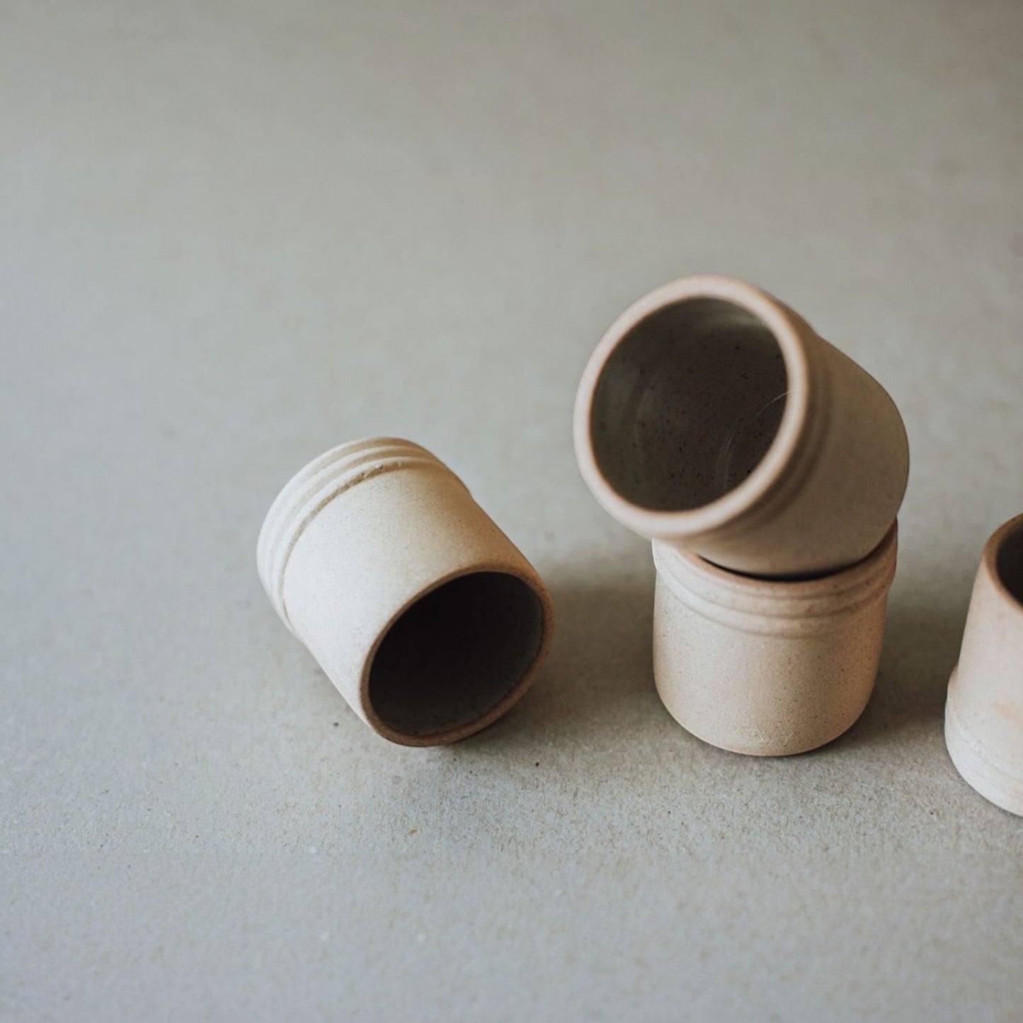 Four ceramic mezcal tasting cups arranged in a row on minimal backdrop