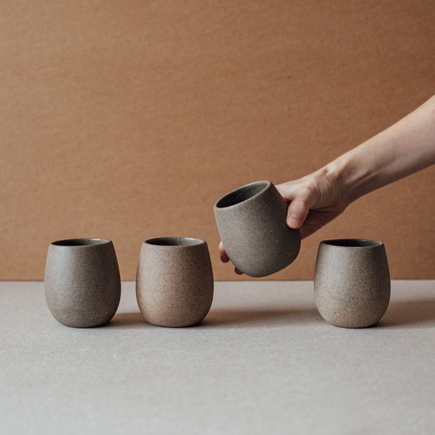 Round stoneware cup lying on its side, highlighting the thick rim and matte natural texture