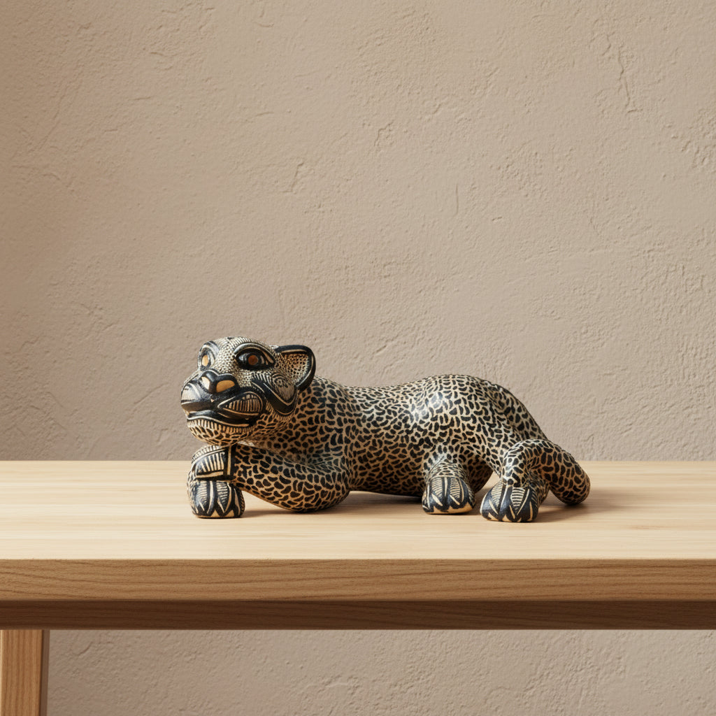 Handcrafted clay jaguar sculpture in a reclining pose on a wooden table