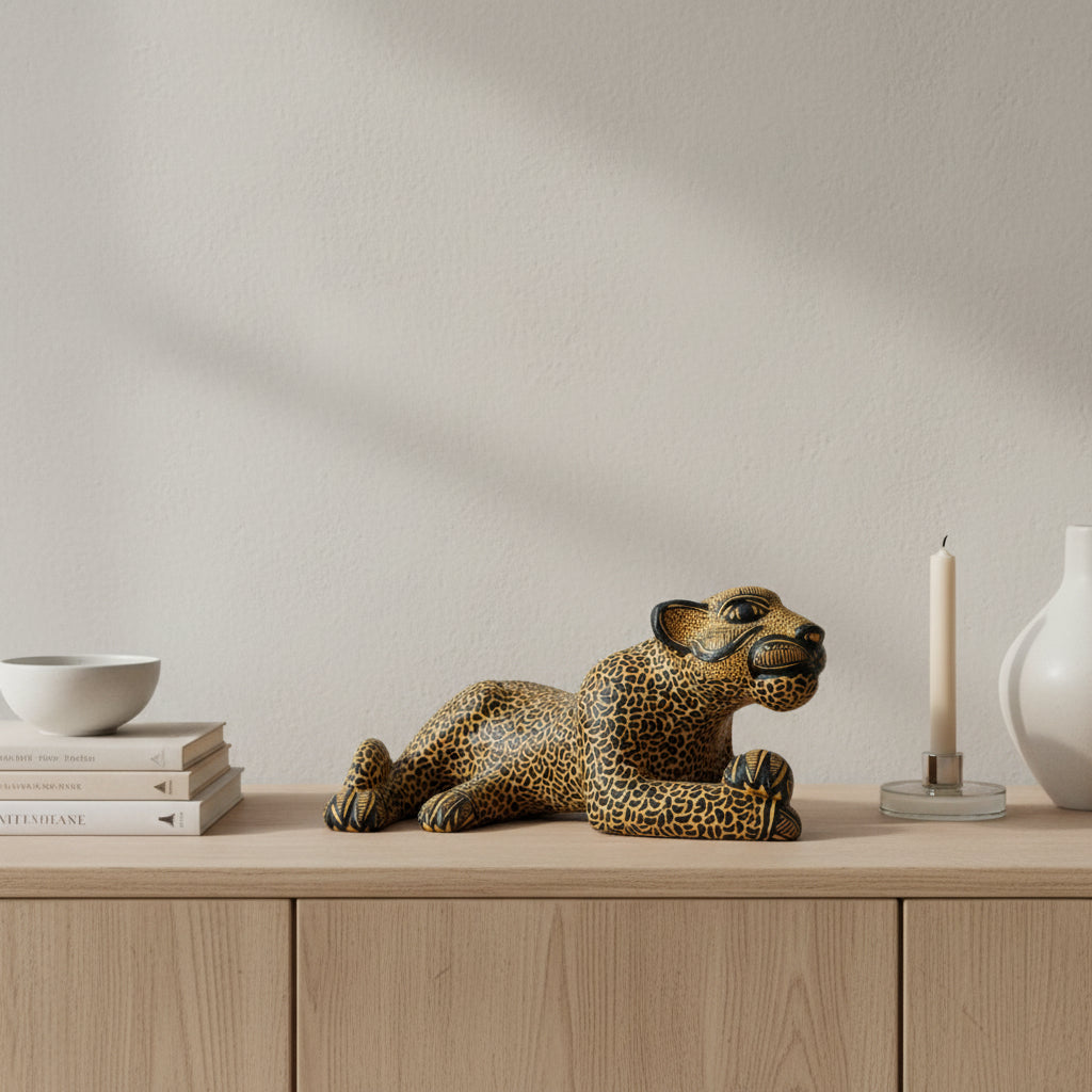 Handcrafted Mayan clay jaguar figurine displayed on a wooden surface with candle and ceramic vase