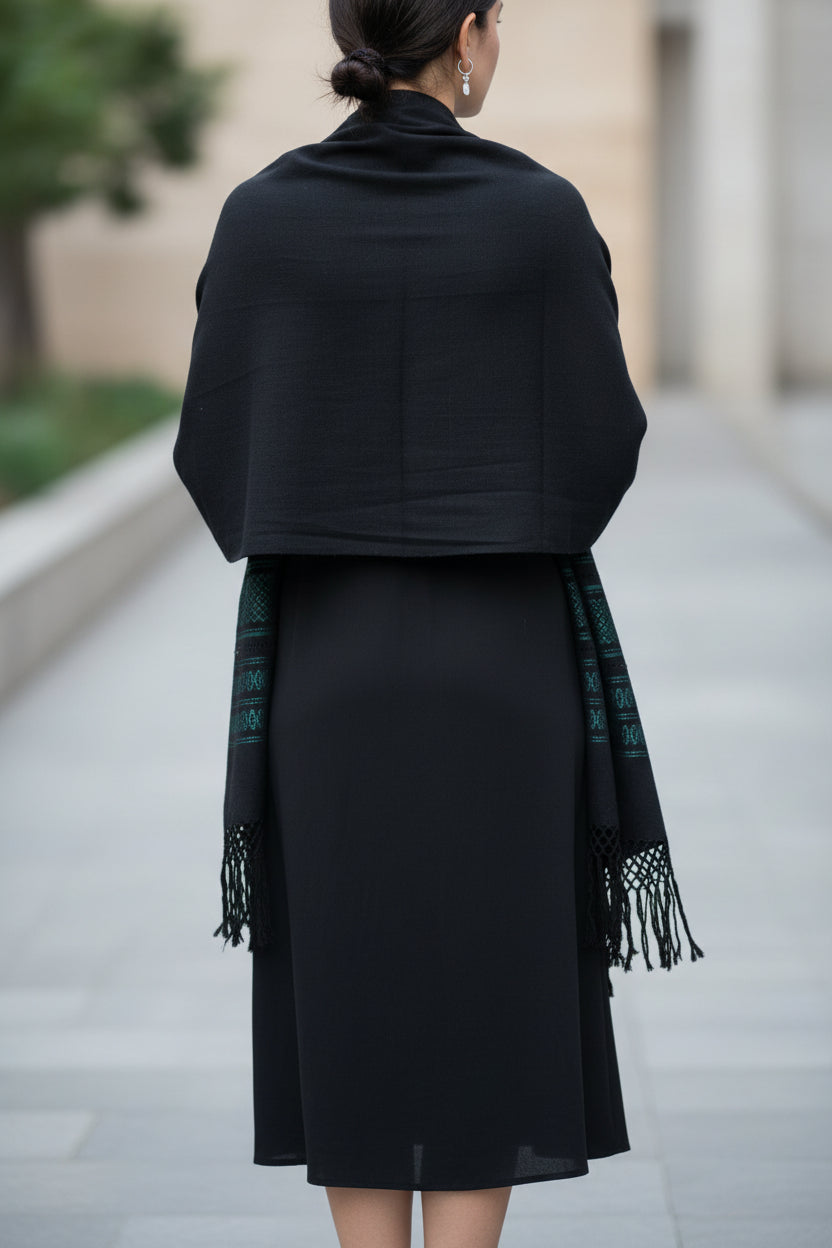 Back view of black handwoven cotton shawl worn as a wrap, showing coverage and drape