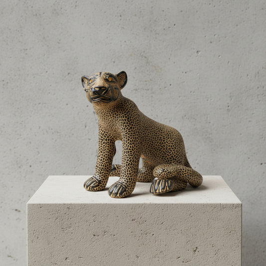 Seated Mayan jaguar clay sculpture on a white pedestal against a gray textured wall