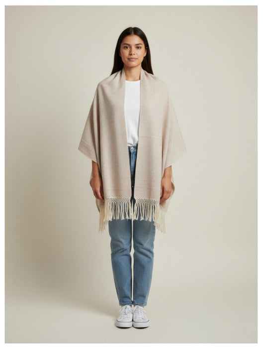Woman wearing a beige handwoven cotton shawl with fringe, styled as a wrap on a neutral studio background