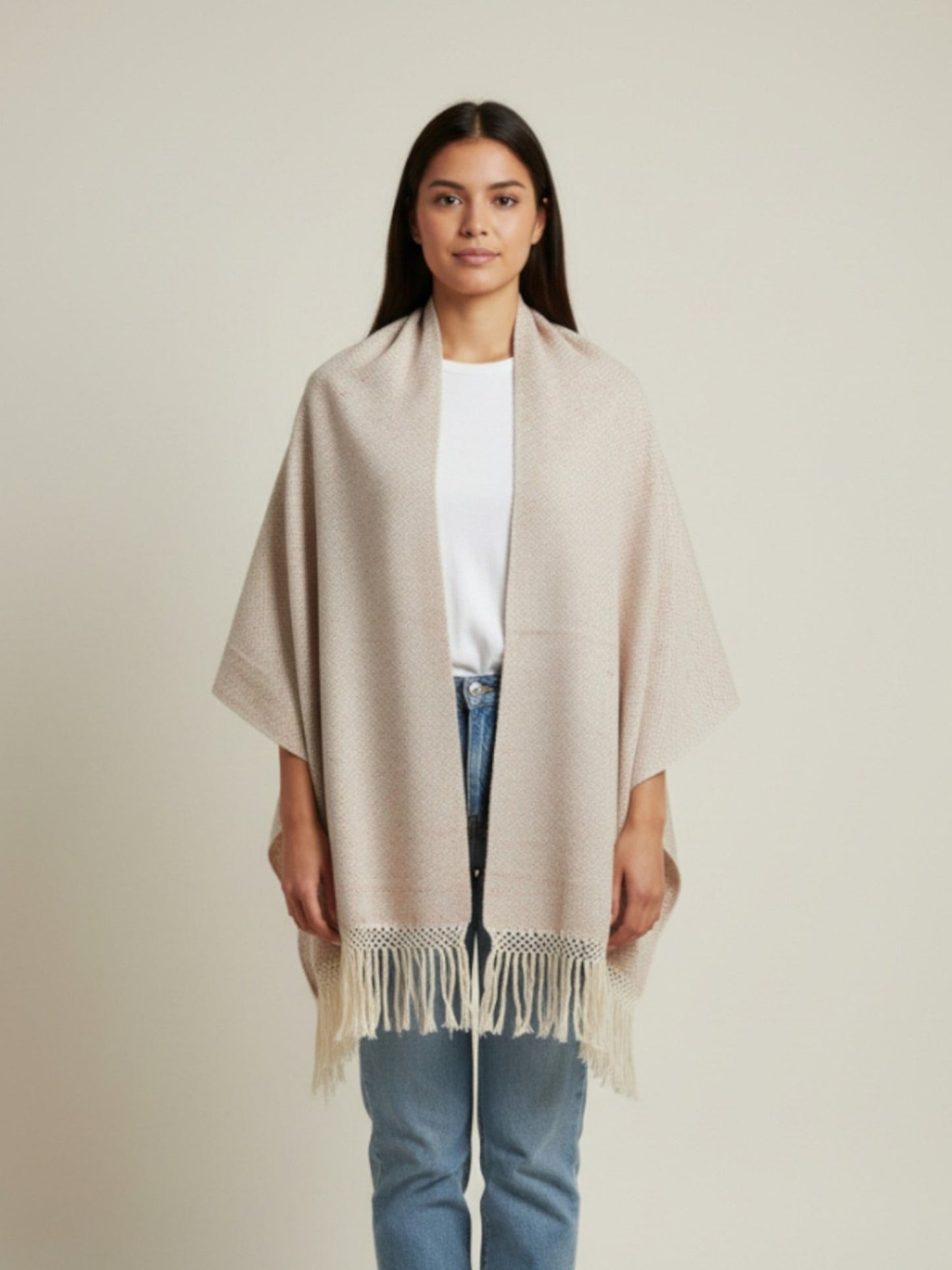 Woman wearing a beige handwoven cotton shawl with fringe, styled as a wrap on a neutral studio background