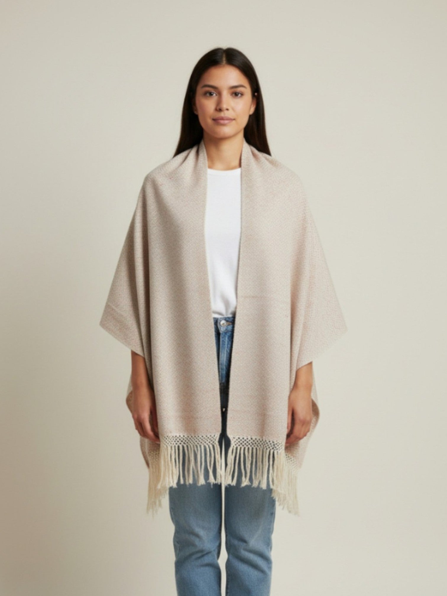 Woman wearing a beige handwoven cotton shawl with fringe, styled as a wrap on a neutral studio background