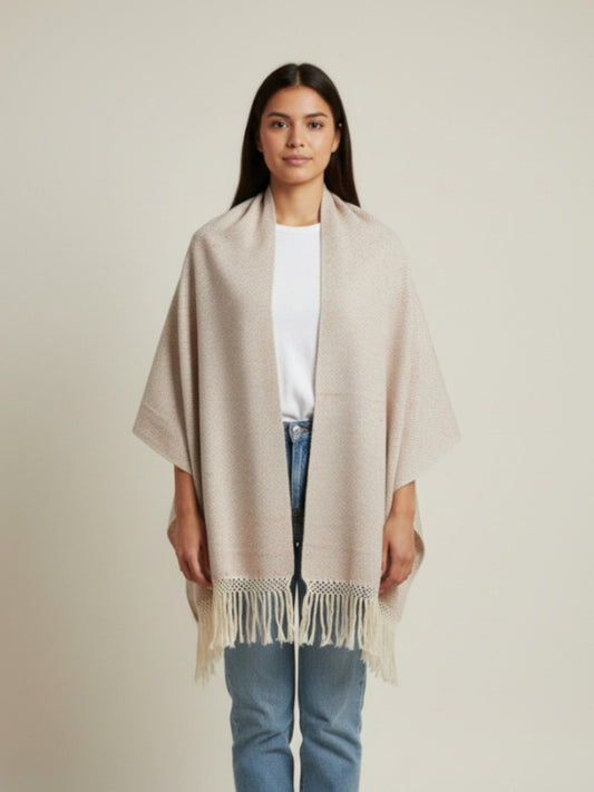 Woman wearing a beige handwoven cotton shawl with fringe, styled as a wrap on a neutral studio background