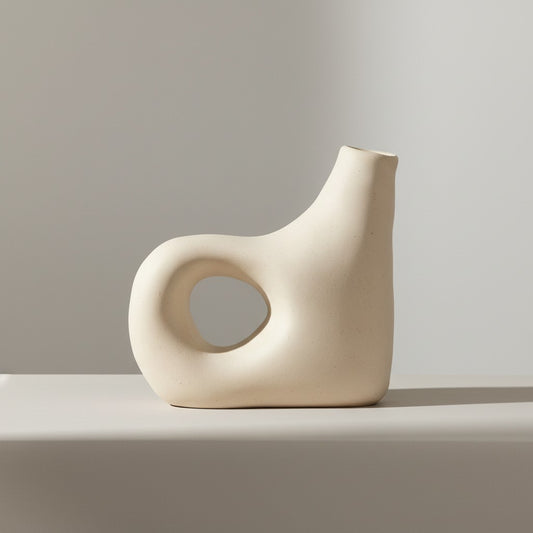 Handmade curved spout ceramic vase displayed on a light grey surface.