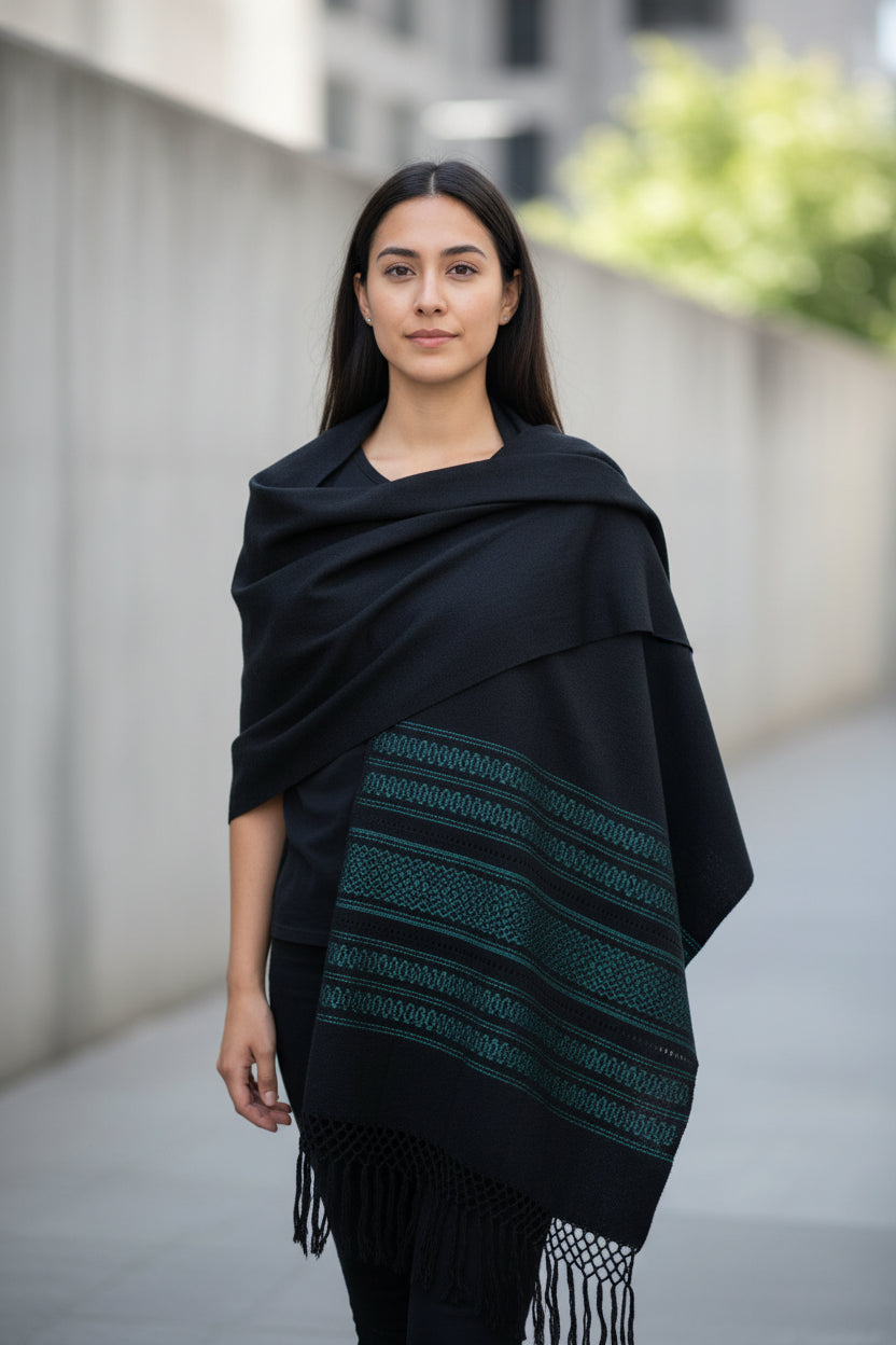 Woman wearing a black cotton rebozo shawl with woven borders in an urban setting