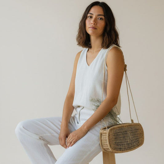 Model holding a handwoven rectangular jonote basket bag with dried flowers, neutral background